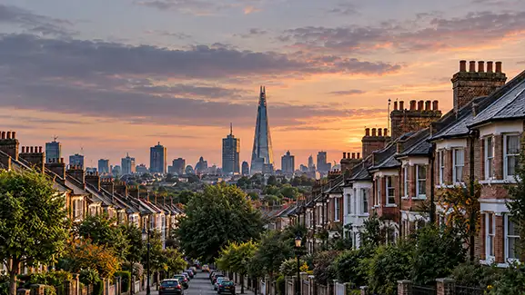 London residential street with terraced houses and The Shard visible on the skyline at sunset.